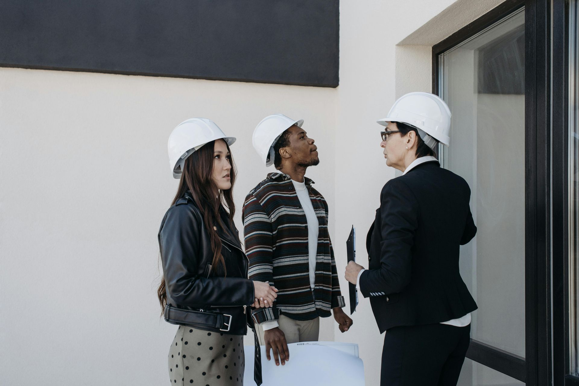 A group of people wearing hard hats are standing in front of a building.