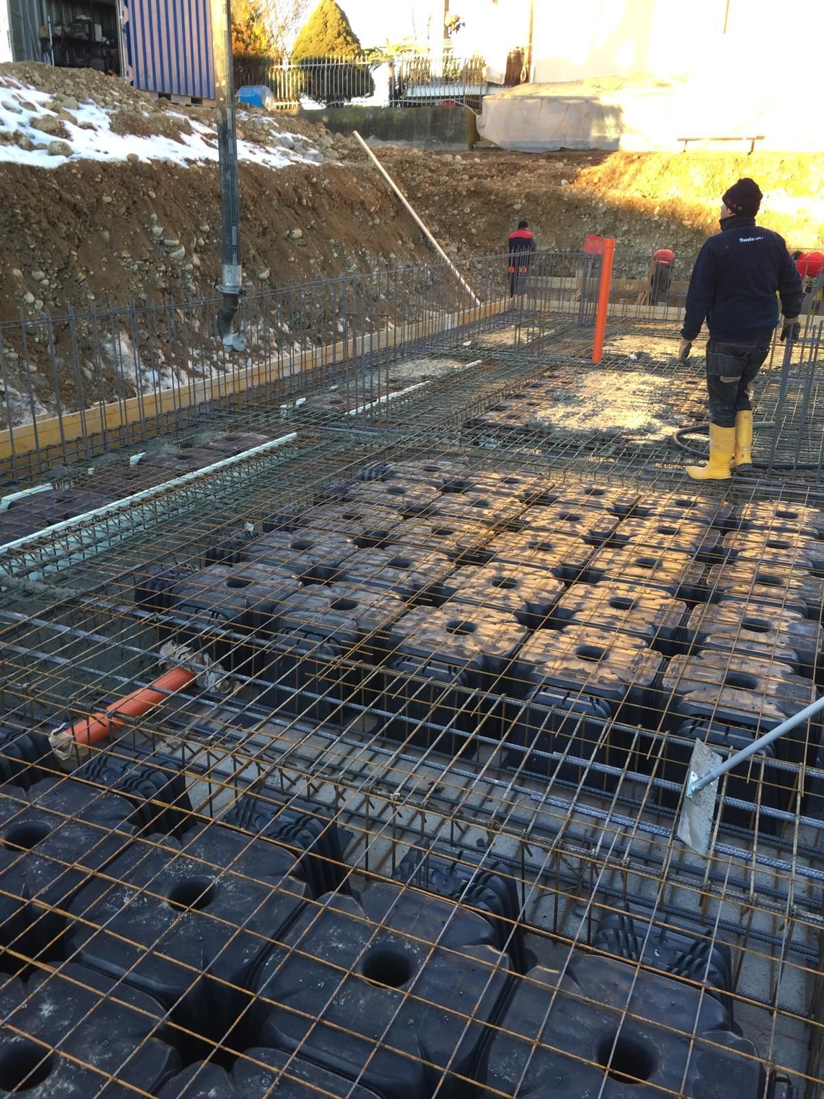 Cantiere: operai vicino alle barre d'armatura e alle casseforme nere, in preparazione del getto di calcestruzzo.