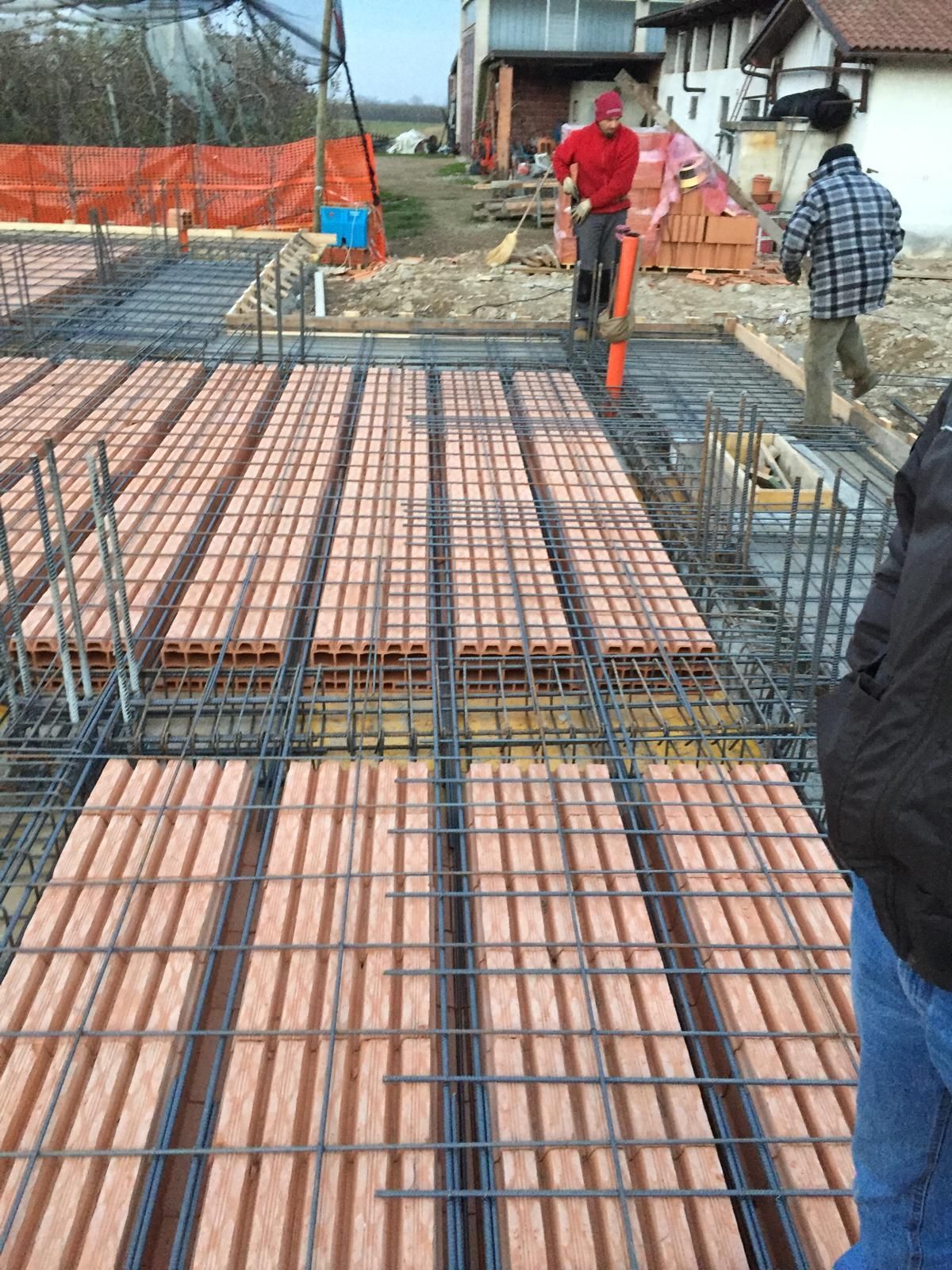 Cantiere con operai, barre d'armatura e mattoni, in preparazione per il getto di calcestruzzo.