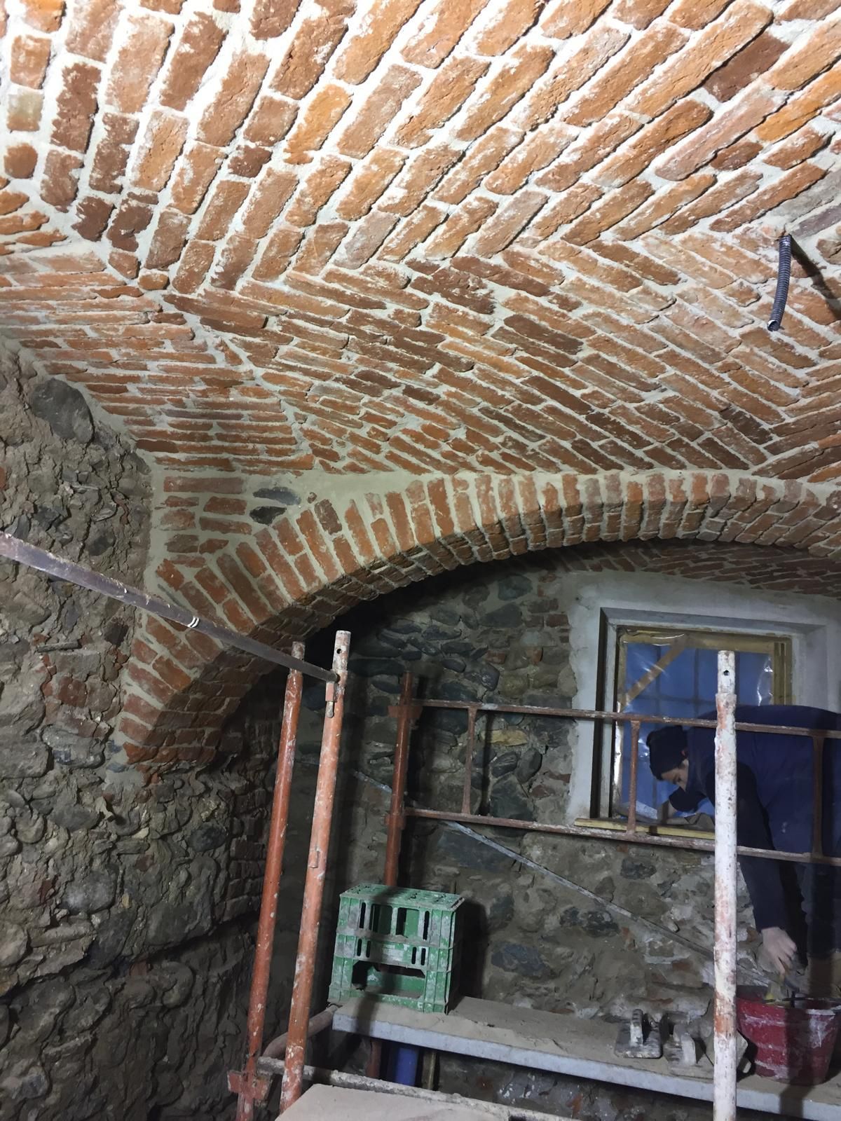 Soffitto a volta in mattoni in costruzione; impalcature, muri in pietra.