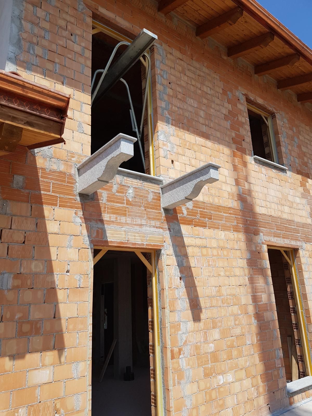 Edificio in costruzione; esterno in mattoni, infissi di porte e finestre, cornicioni in cemento.