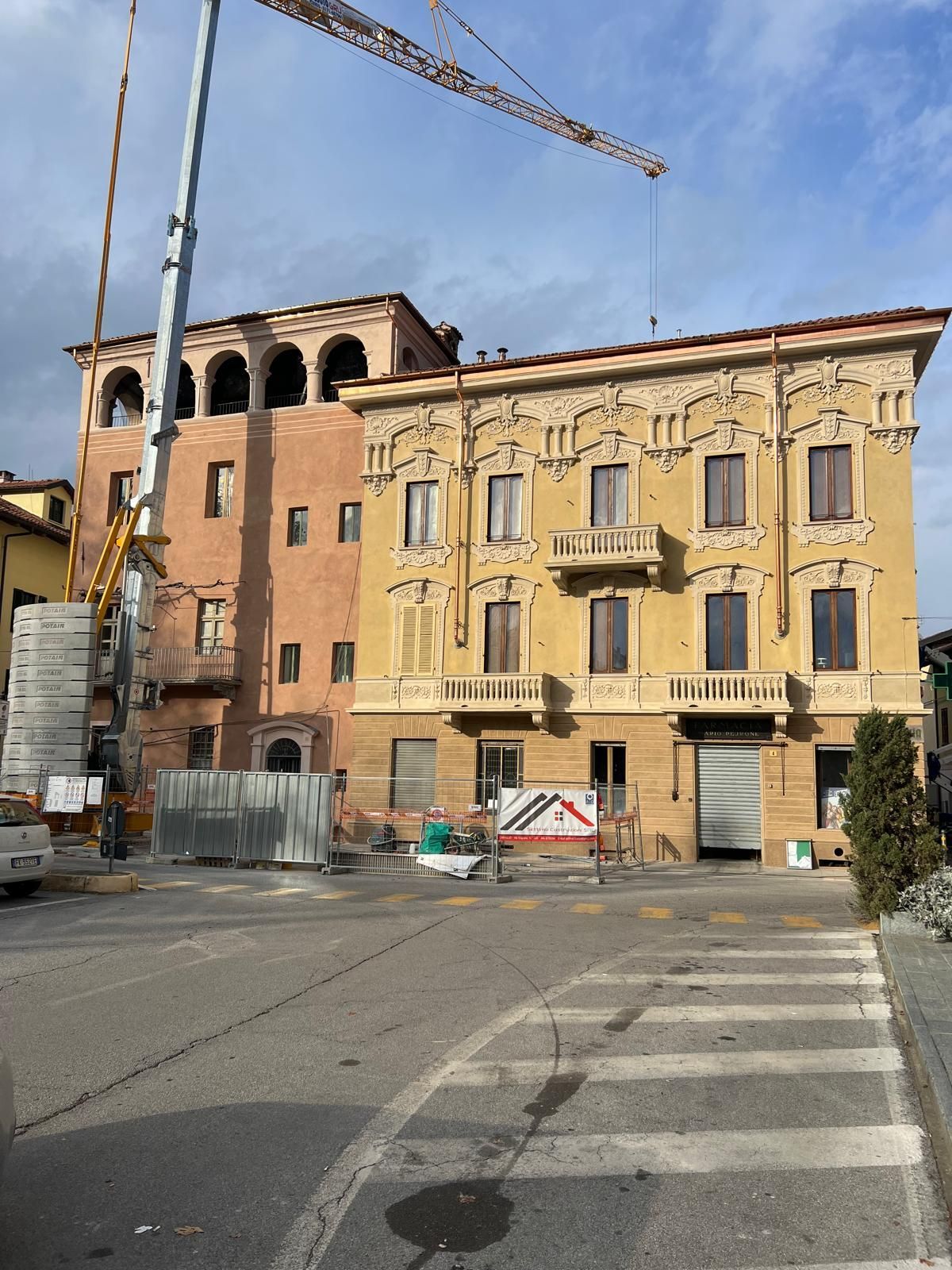 Edifici in costruzione con una gru e barricate su una strada.