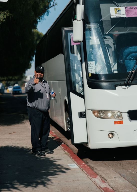 Smiling team member beside bus ready to answer charter inquiries
