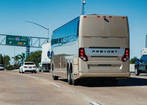 Back view of charter bus driving through San Diego traffic during peak travel hours