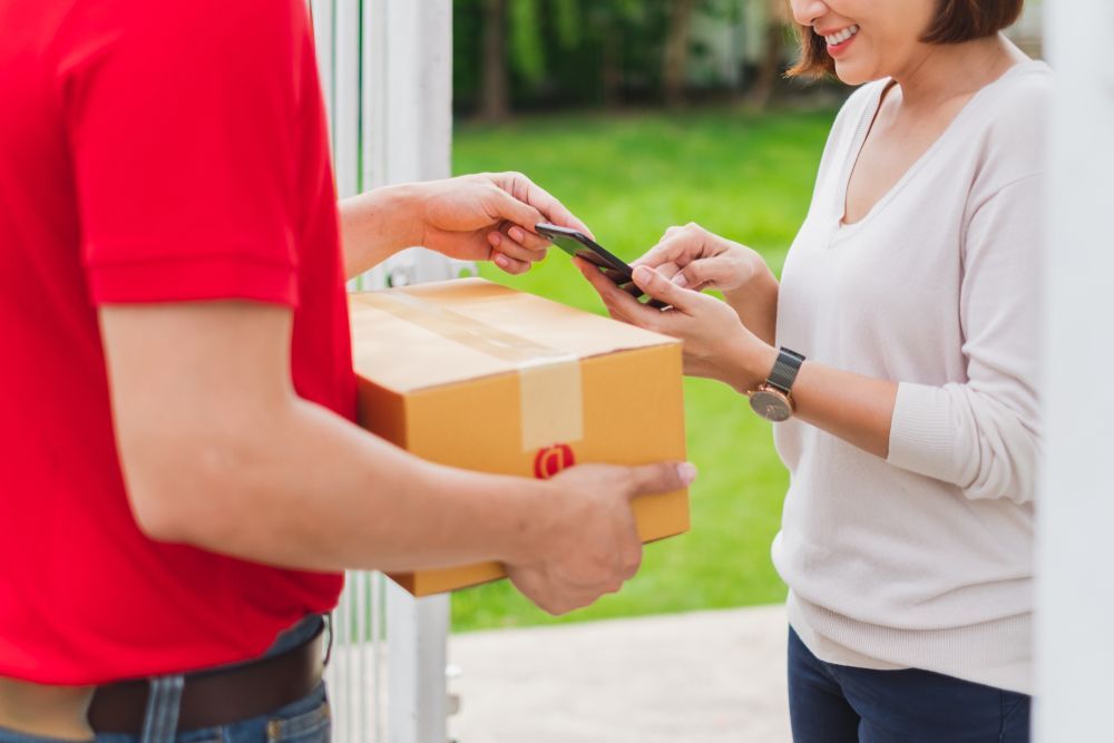 A Delivery Man is Handing a Box to a Woman — Express Couriers Mackay in Paget, QLD