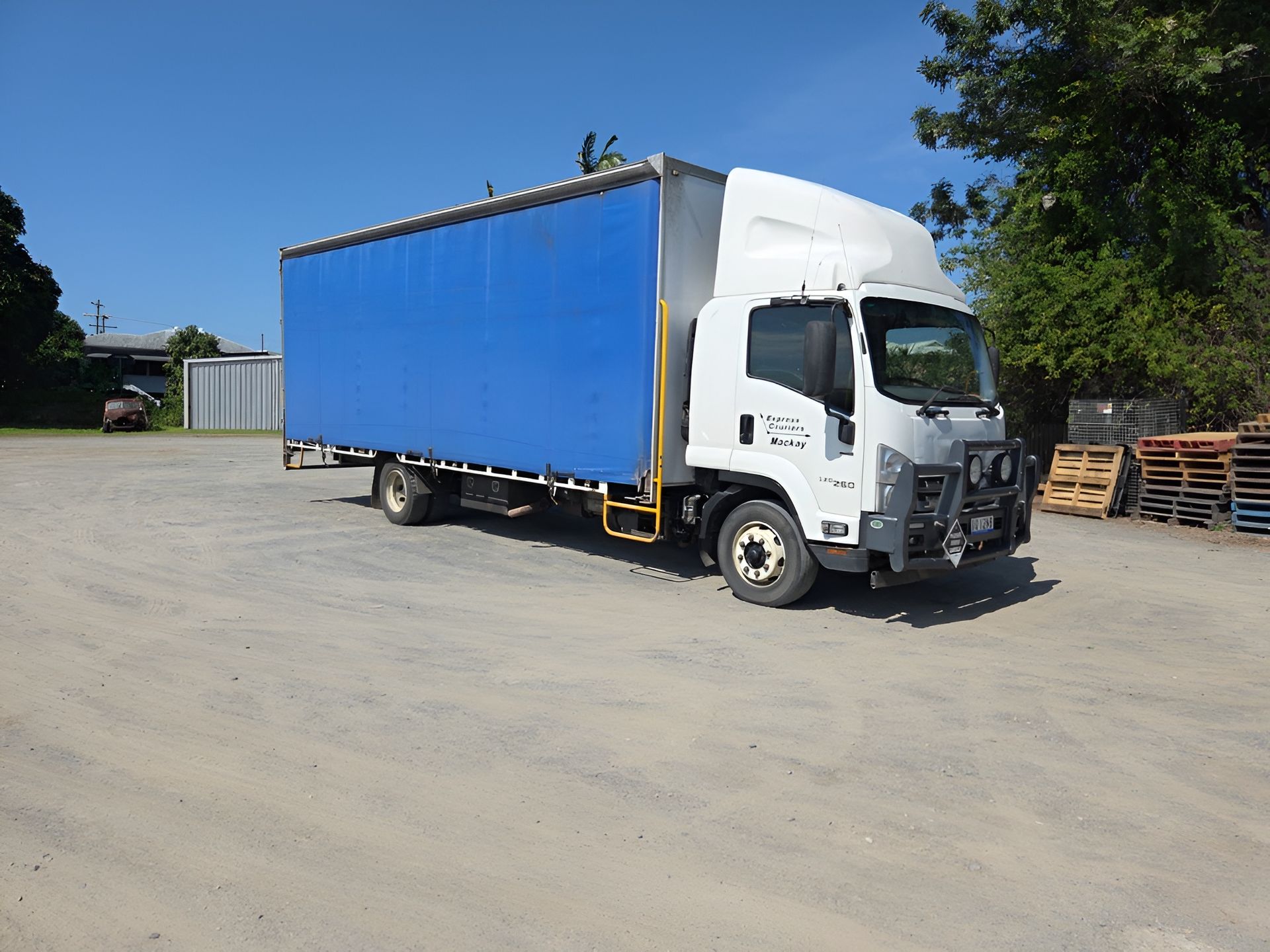 Blue and white box truck parked on gravel under a blue sky — Express Couriers Mackay in West Mackay, QLD