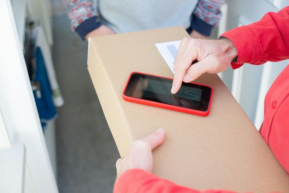 A Person Is Holding A Cardboard Box And Using A Cell Phone — Express Couriers Mackay in West Mackay, QLD