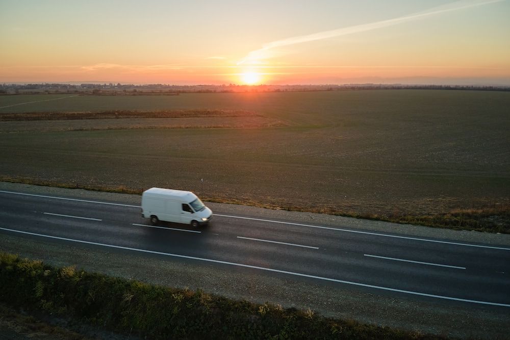 An Aerial View of a White Van Driving Down a Road at Sunset — Express Couriers Mackay in Moranbah, QLD