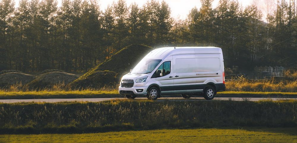 A White Van is Driving Down a Road Next to a Field — Express Couriers Mackay in Paget, QLD