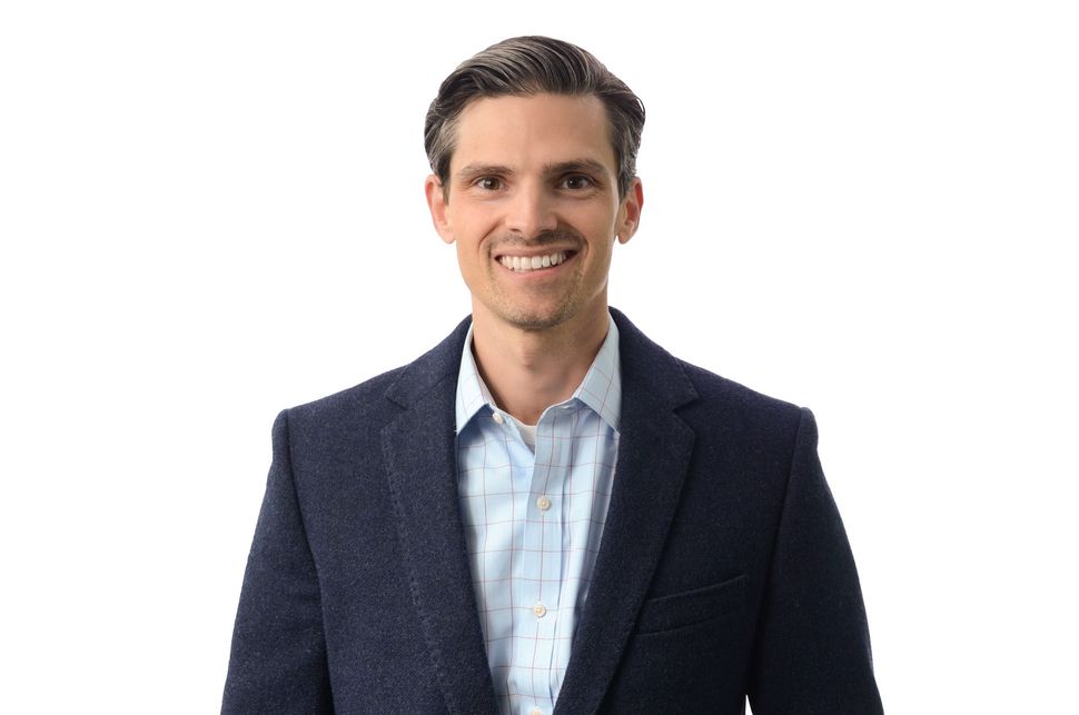 A man in a suit and blue shirt is smiling for the camera.