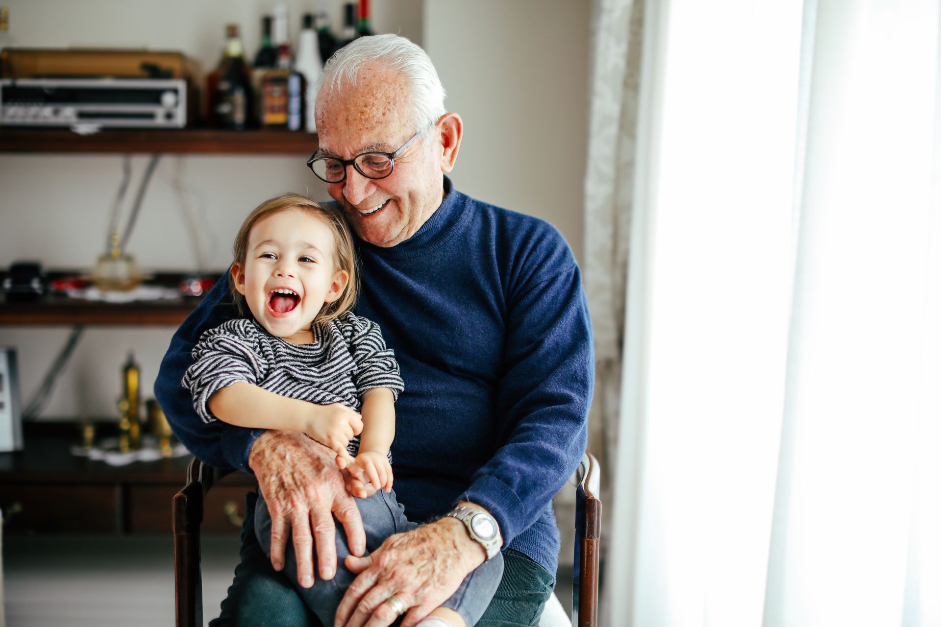 Older man sitting and playing with young child.