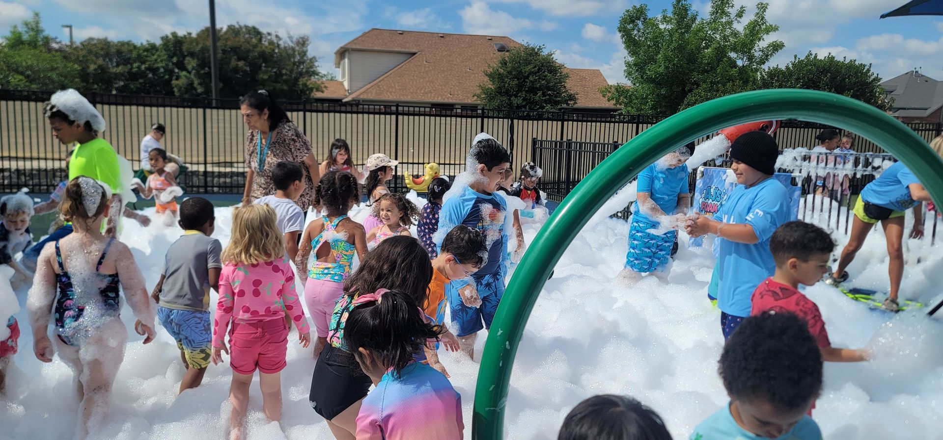 Children playing in a splash pad, with water spraying around colorful summer clothes.