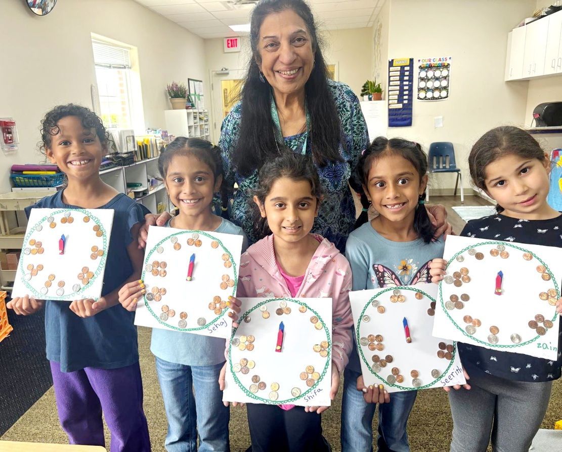 Teacher with five children holding decorated paper plates in a classroom, smiling at the camera.