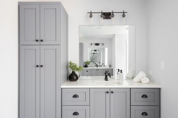 A bathroom with gray cabinets , a sink , and a mirror.