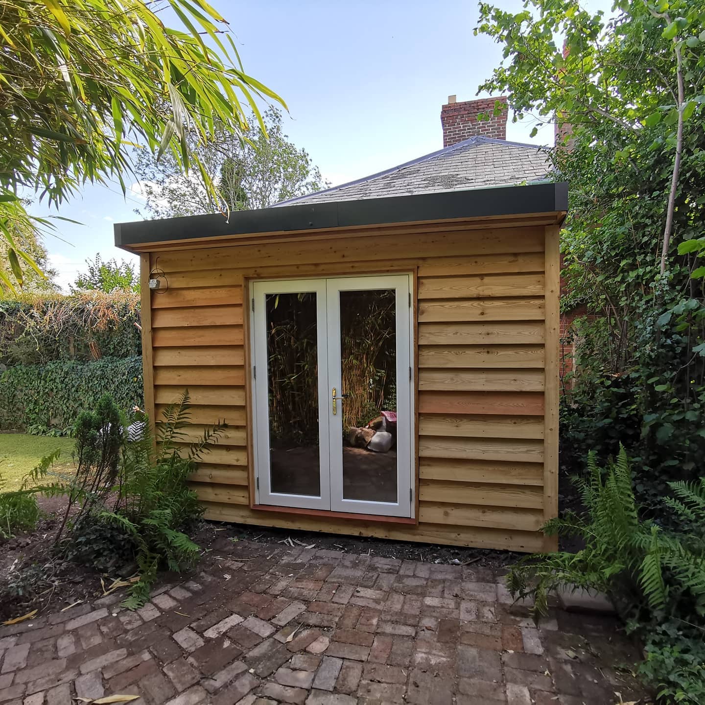 A small wooden house with a brick patio in front of it.