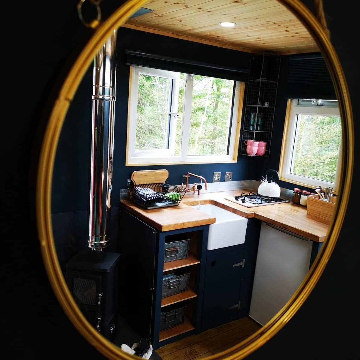 A kitchen with a sink and stove is reflected in a mirror