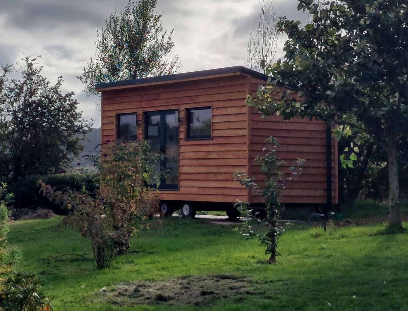 A small wooden house is sitting in the middle of a grassy field