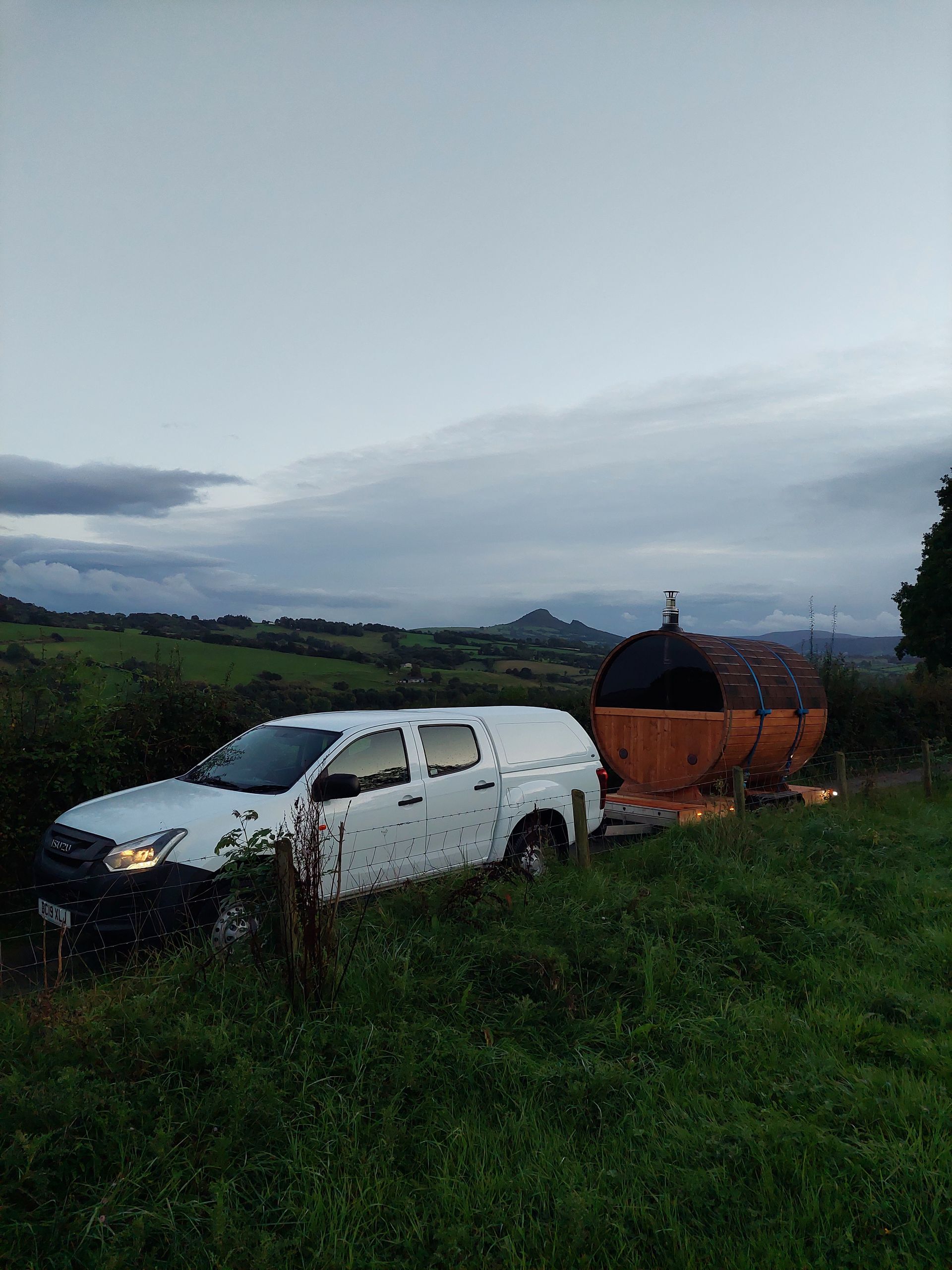 A white truck is parked in the middle of a grassy field.