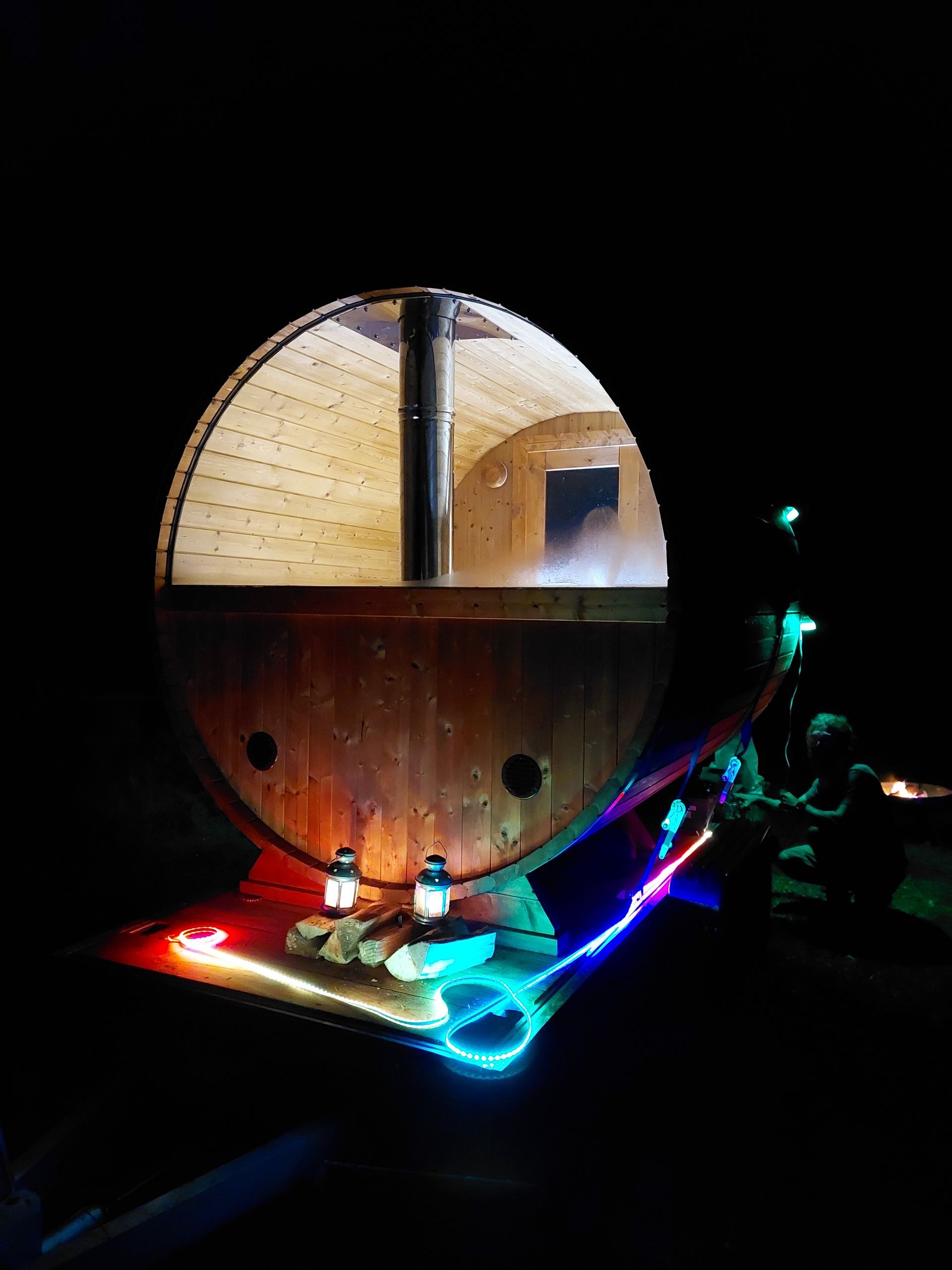 A large wooden barrel is lit up at night.