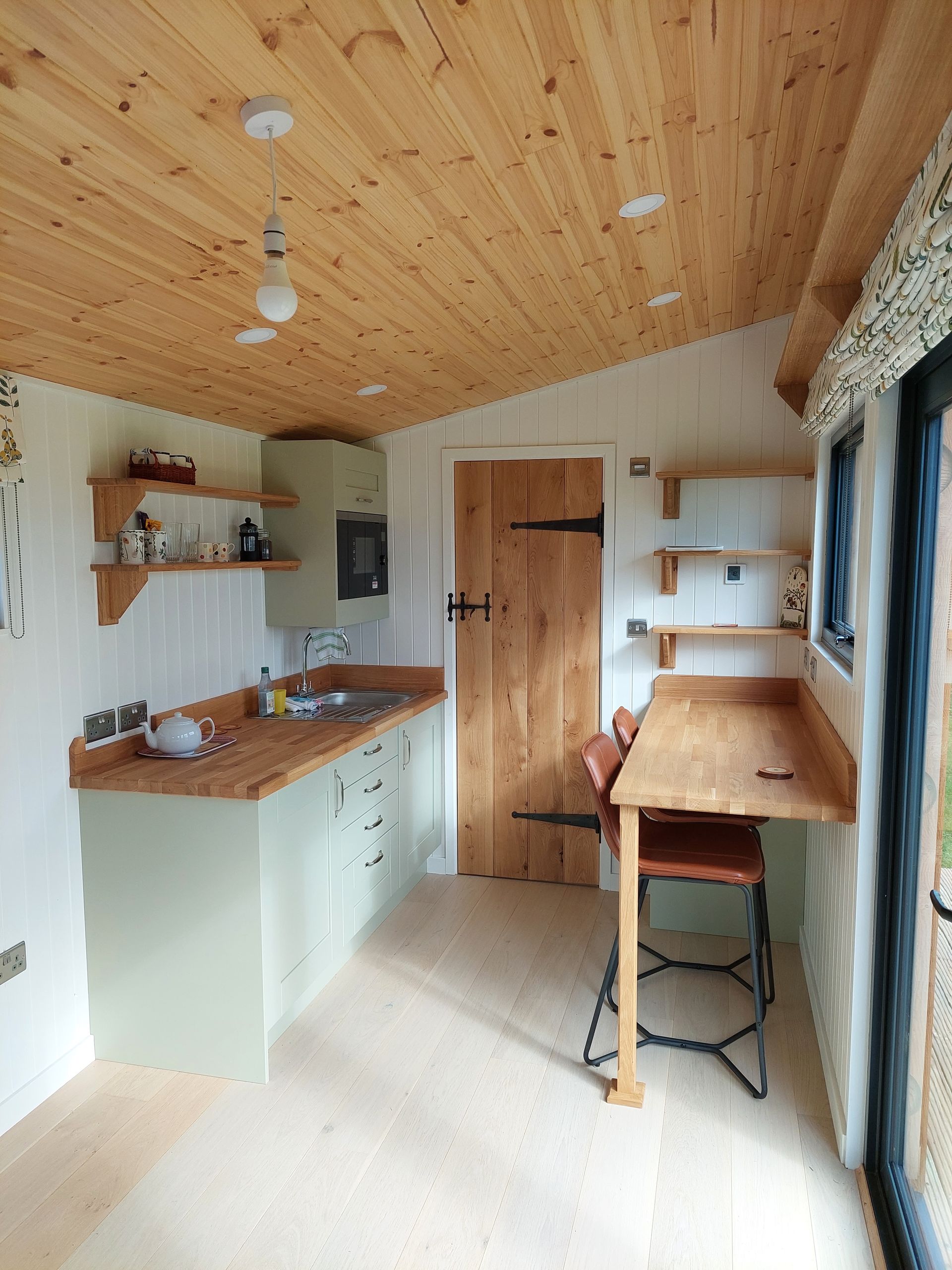 A kitchen with a wooden table and chairs and a wooden ceiling.