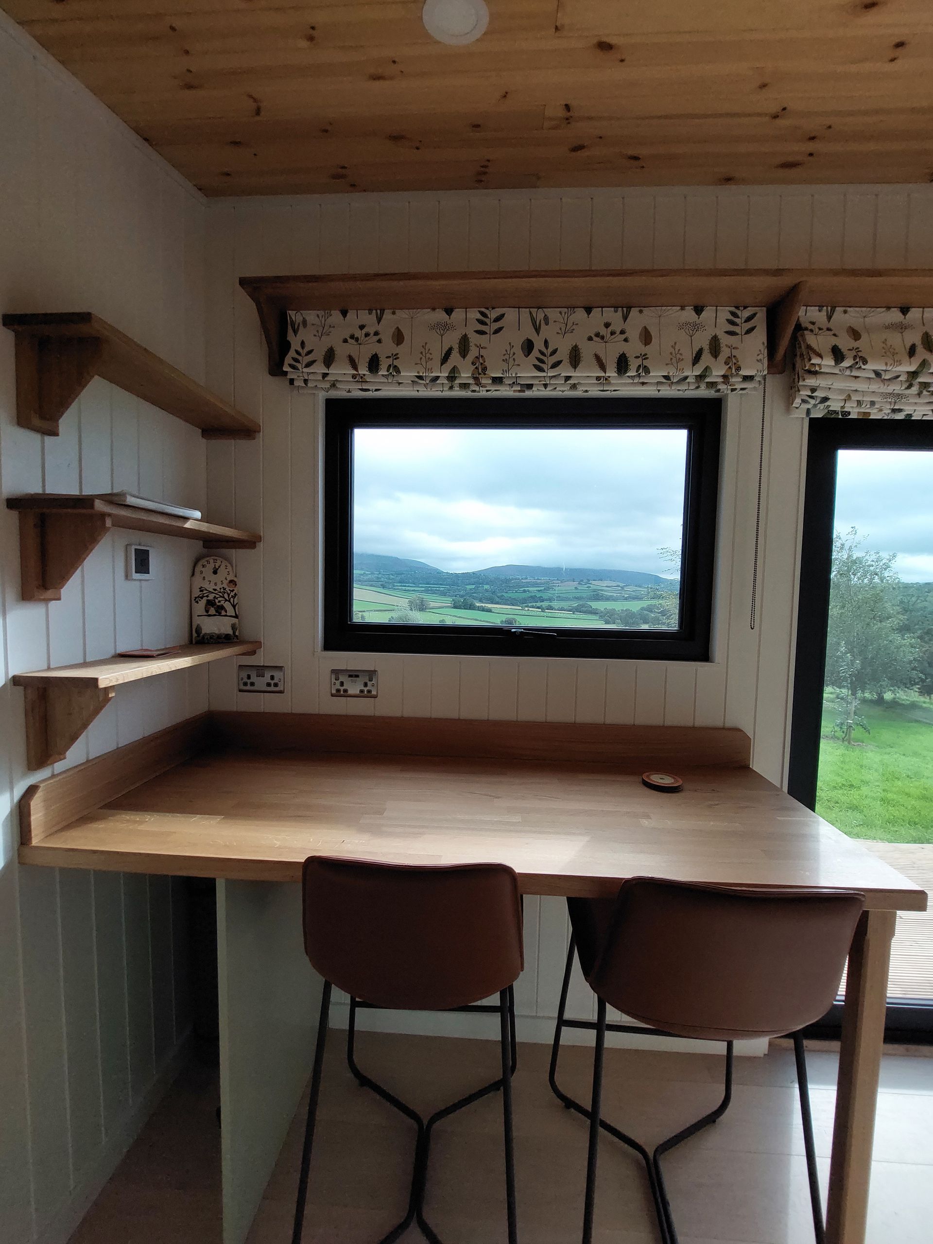 A kitchen with a table and chairs and a window with a view of a field.