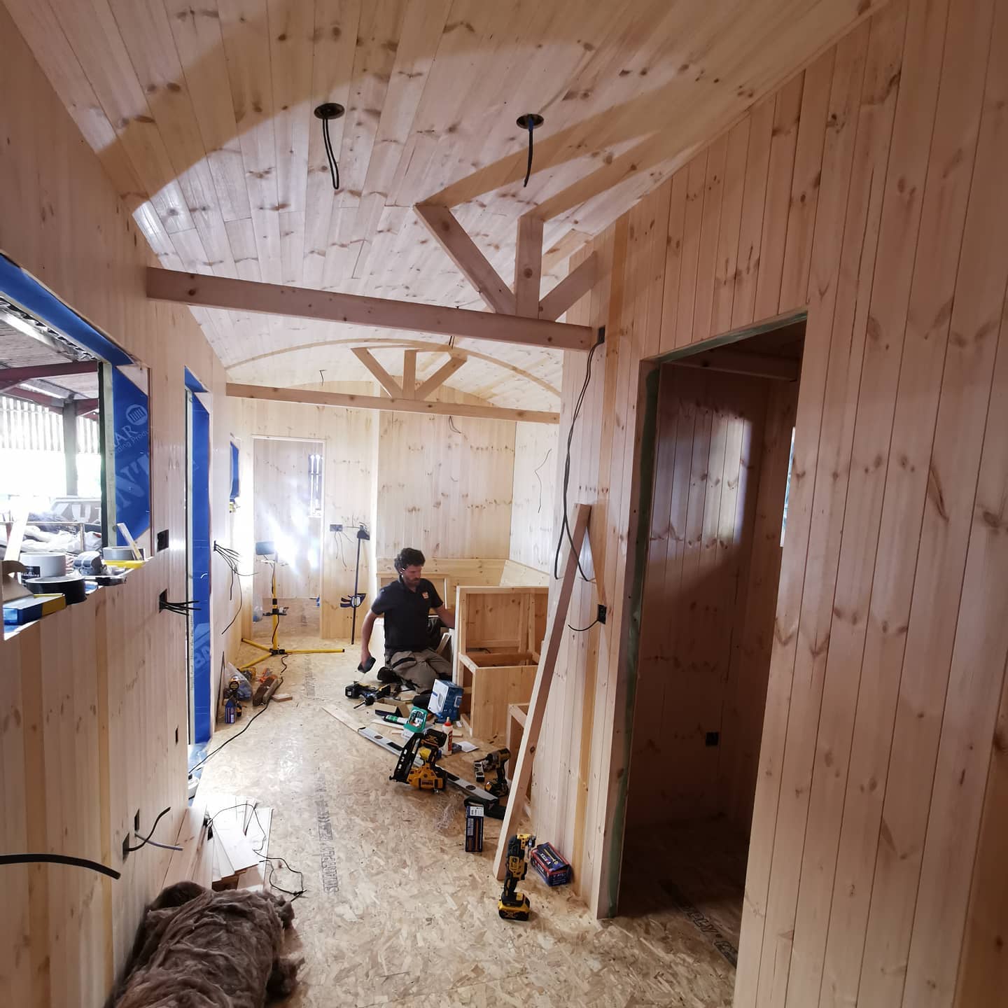 A man is standing in a hallway with wooden walls
