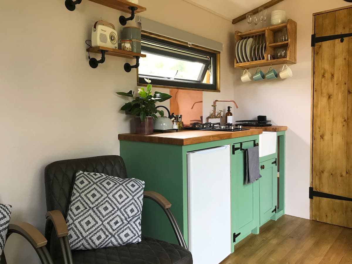 A kitchen with green cabinets , a chair , and a sink.