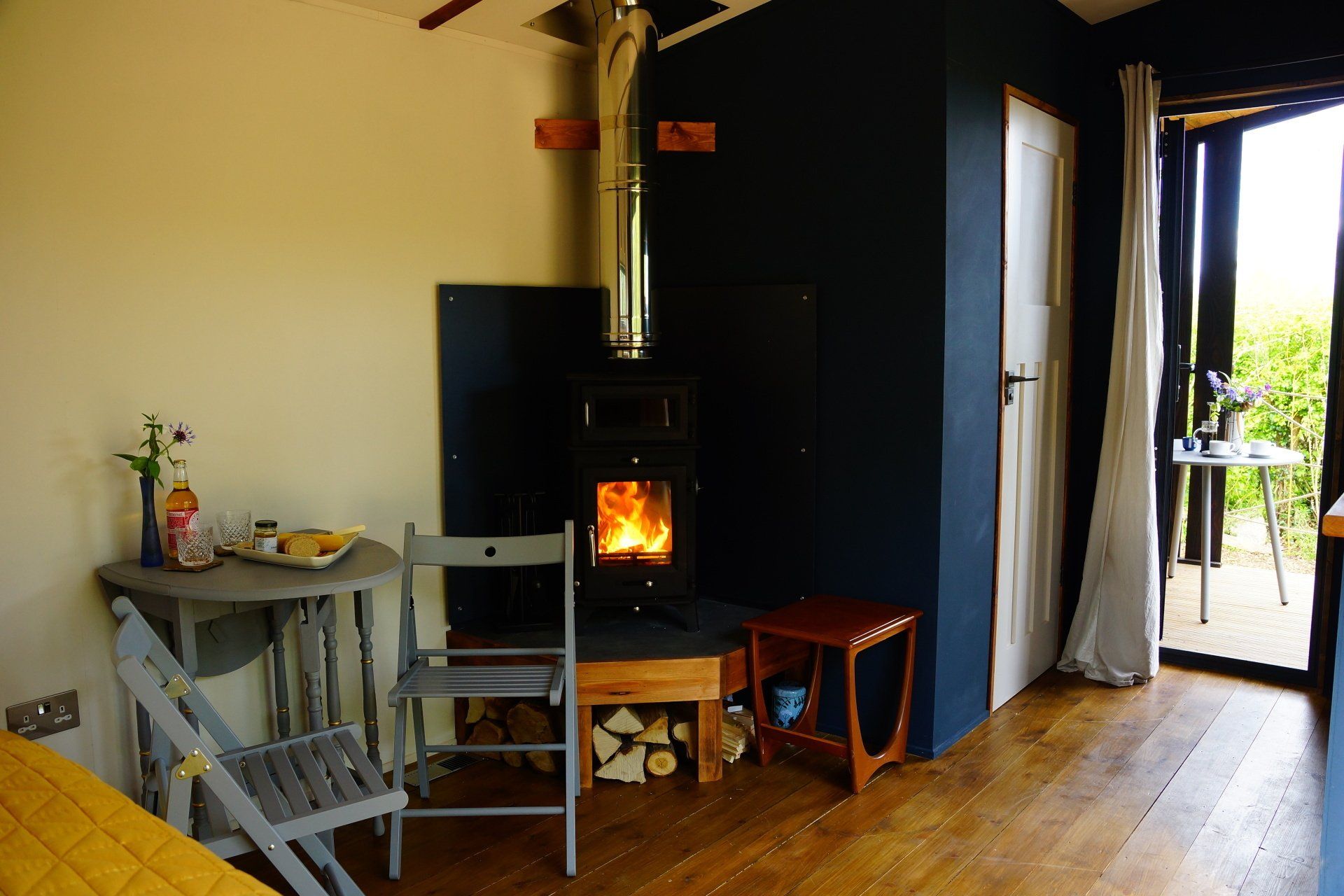 A living room with a wood stove and a table and chairs.