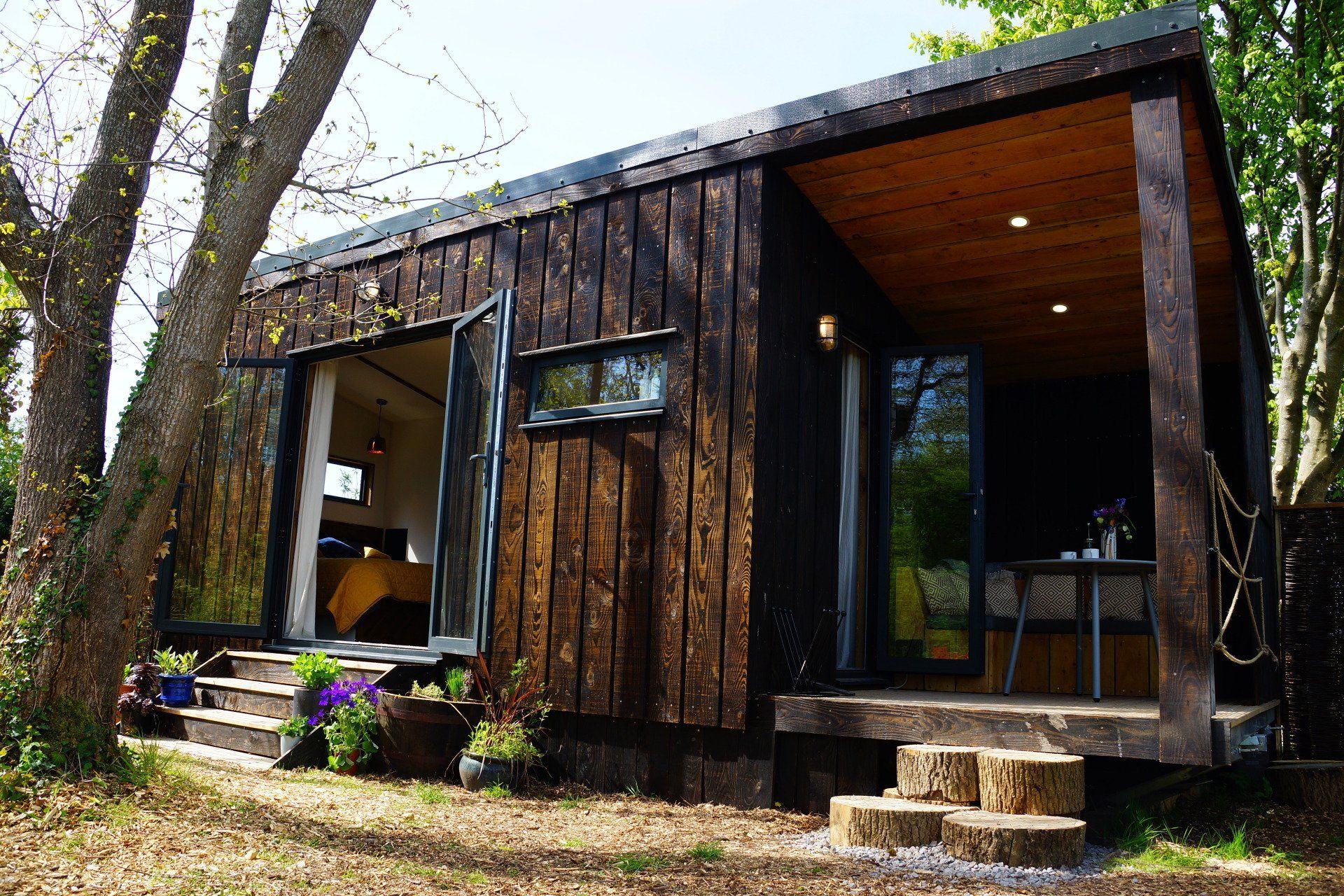 A small wooden house with a porch and stairs in the woods.
