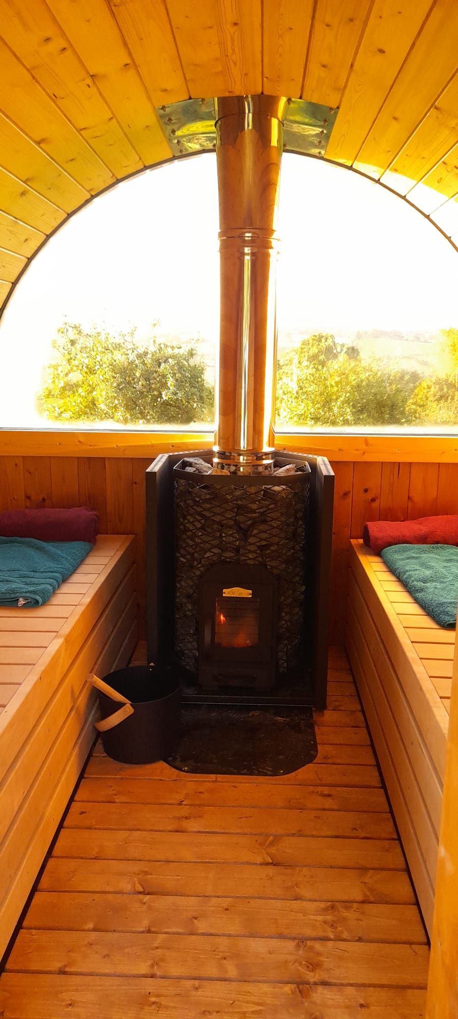 A wooden sauna with a stove and a window.