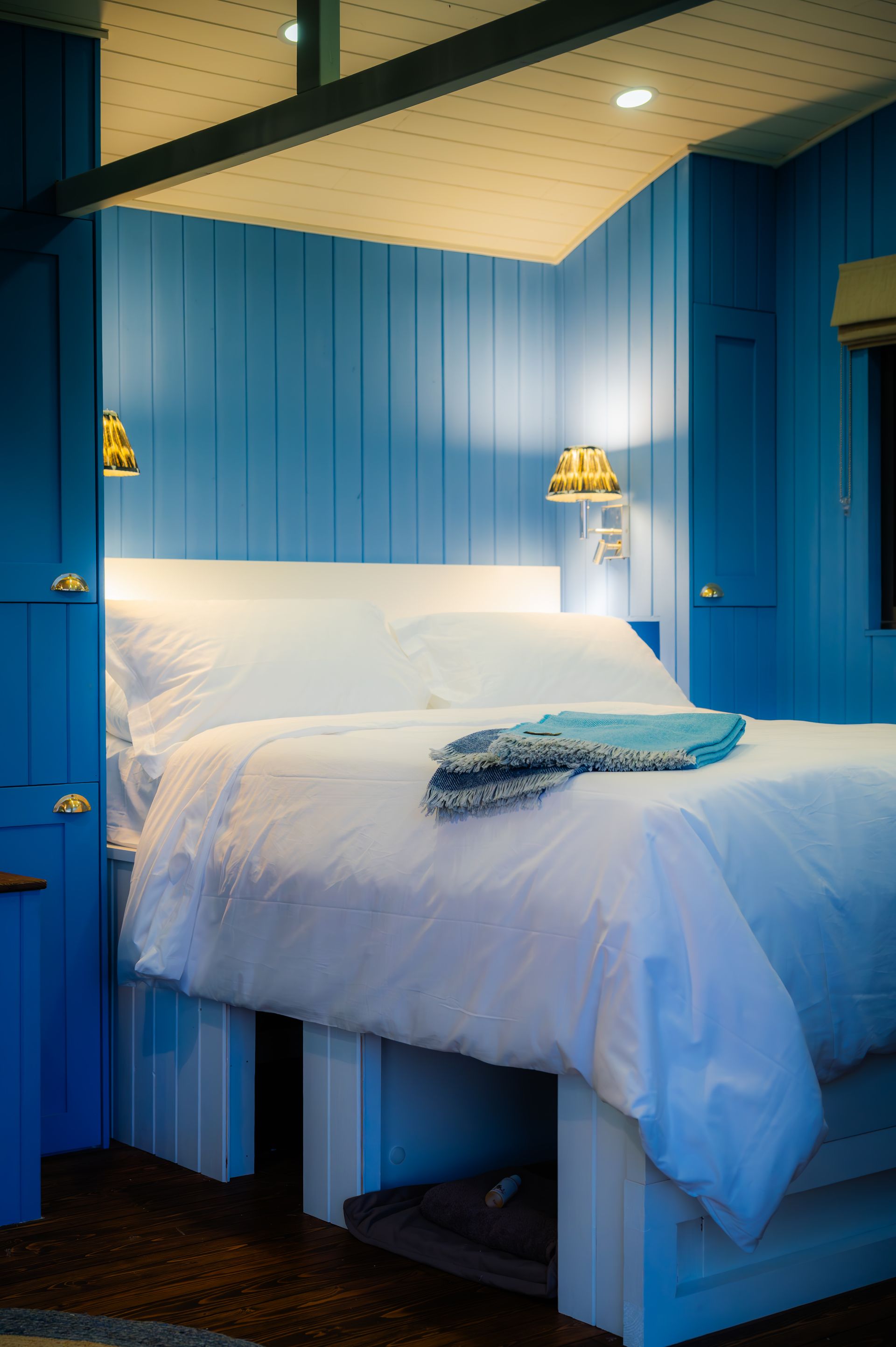 A bedroom with blue walls and a bed with white sheets