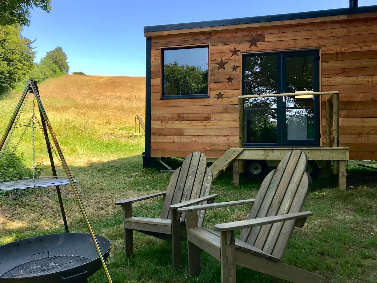 Two wooden chairs are sitting in front of a wooden house.