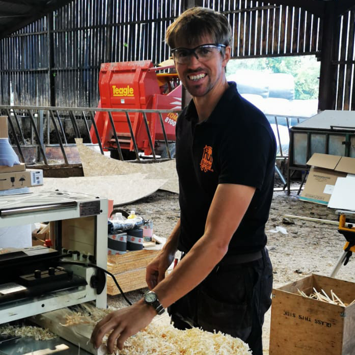 A man wearing glasses is standing in front of a machine that says ' hawks ' on it