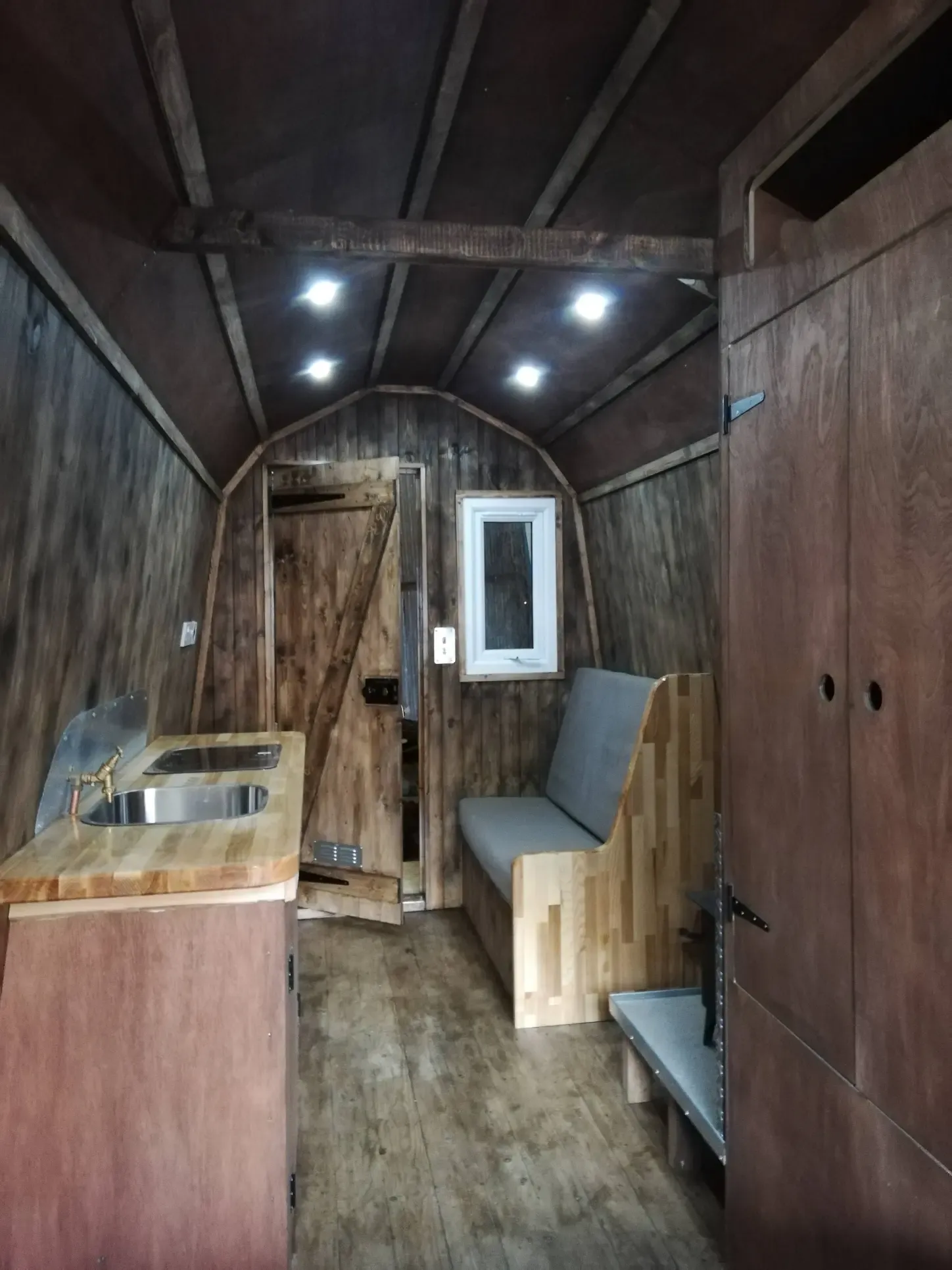 A wooden room with a couch and a sink