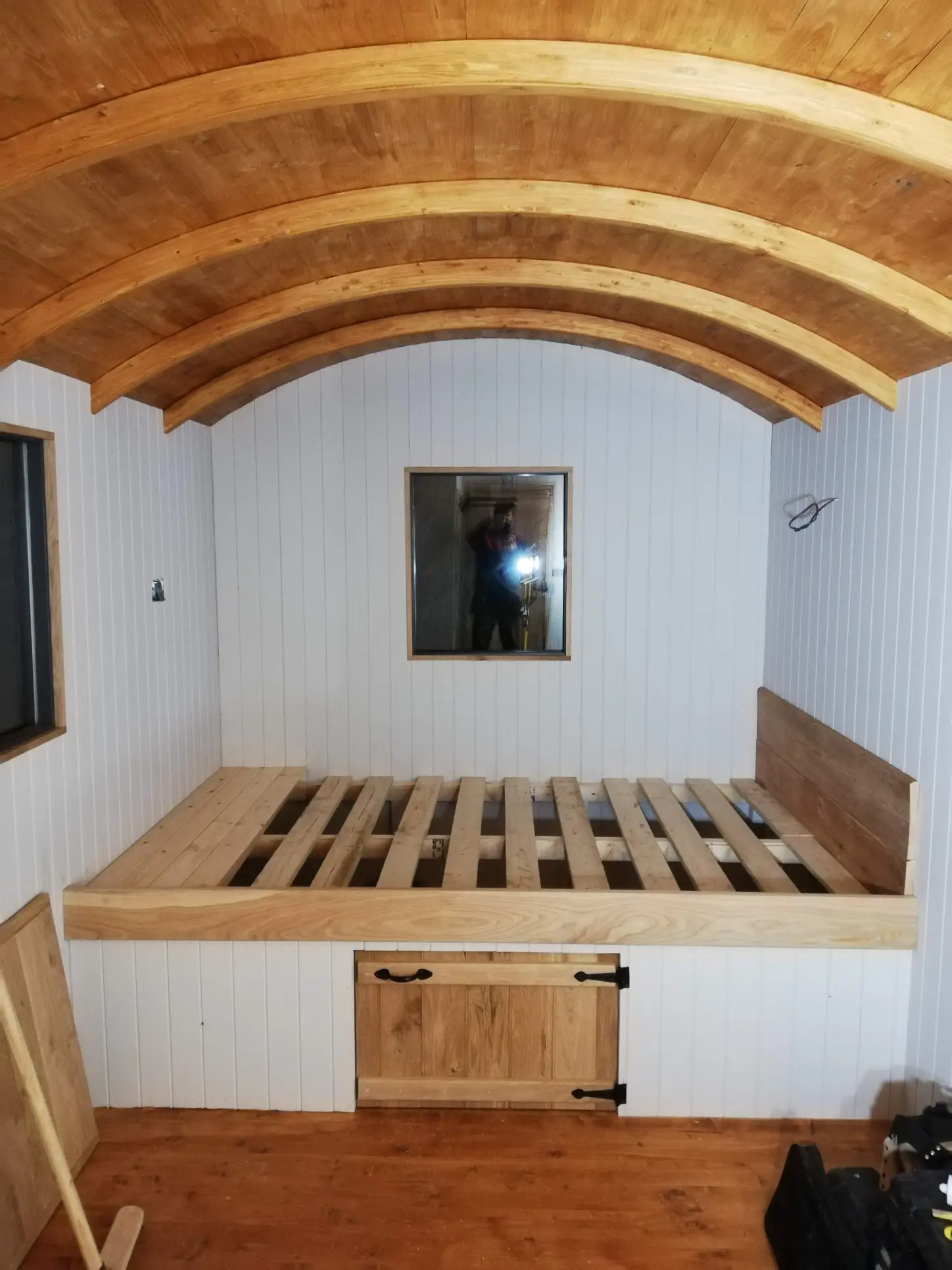 A room with a wooden bed and a mirror on the wall.