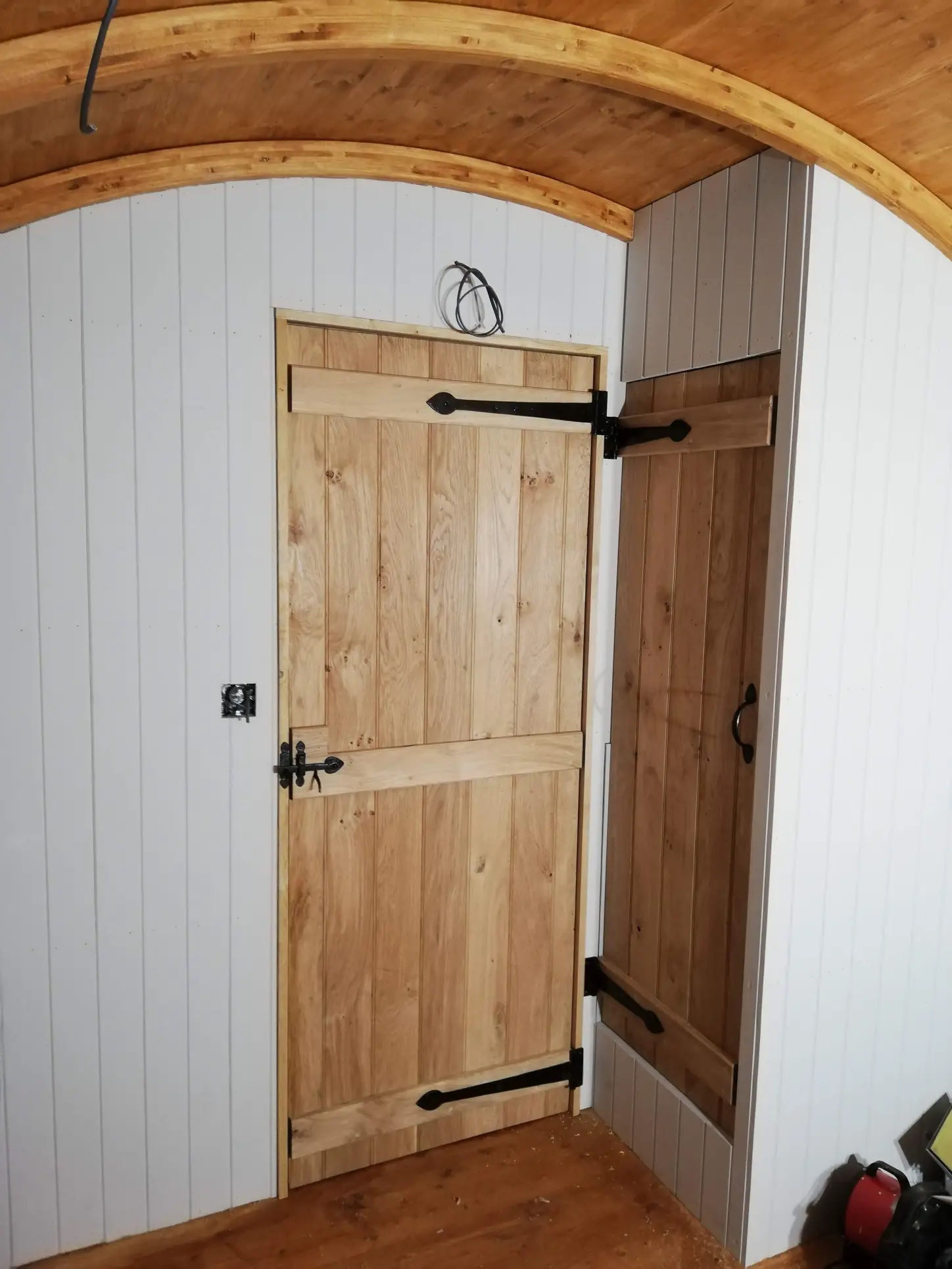 A wooden door in a room with white walls