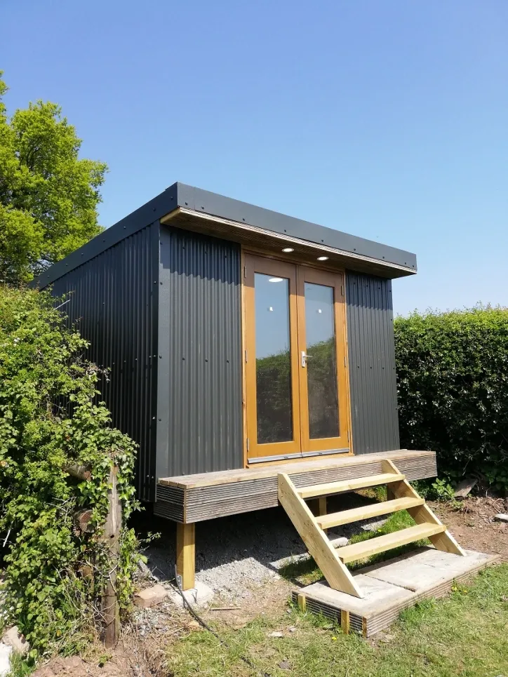A small shed with stairs leading up to it in a yard.