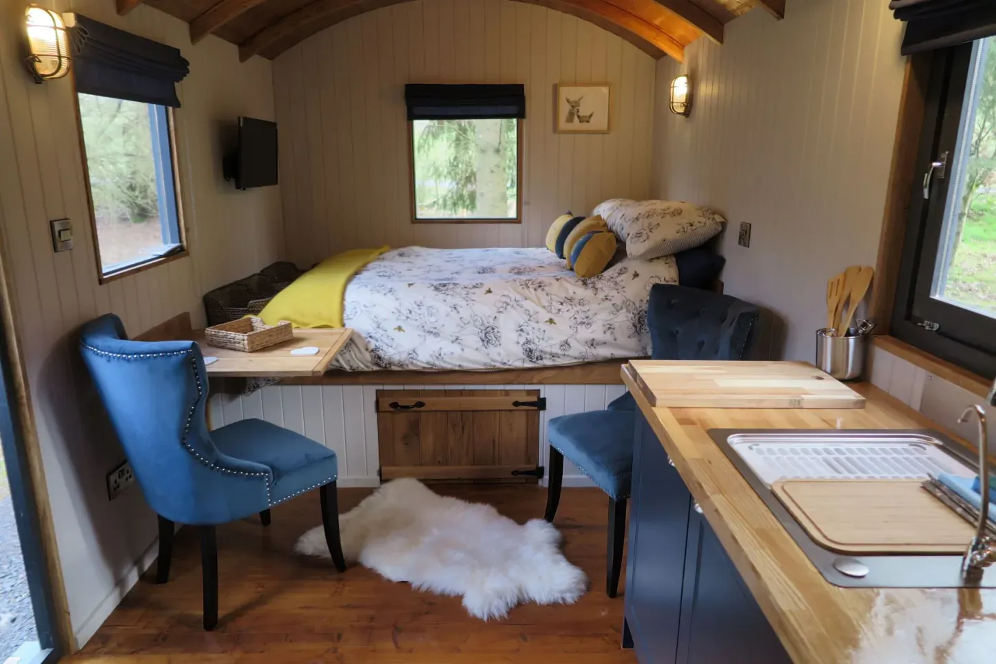 A small room with a bed , chairs , and a sink.