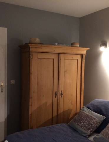 Une chambre avec une armoire en bois et un lit.