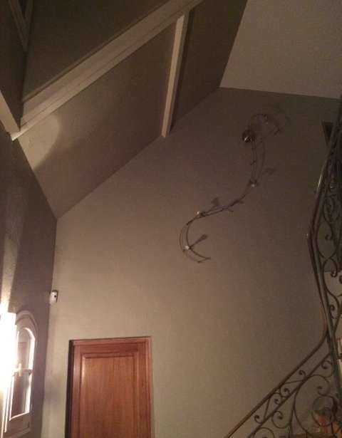 Un couloir avec des escaliers et une porte et une lumière au mur.