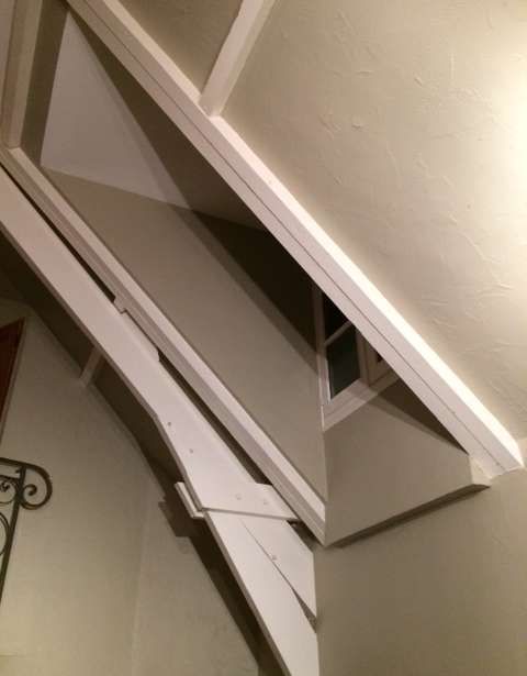 Un escalier avec une fenêtre dans le coin et une rampe blanche.