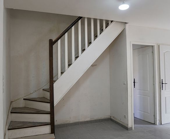 Un escalier blanc avec une rampe en bois dans une pièce vide.