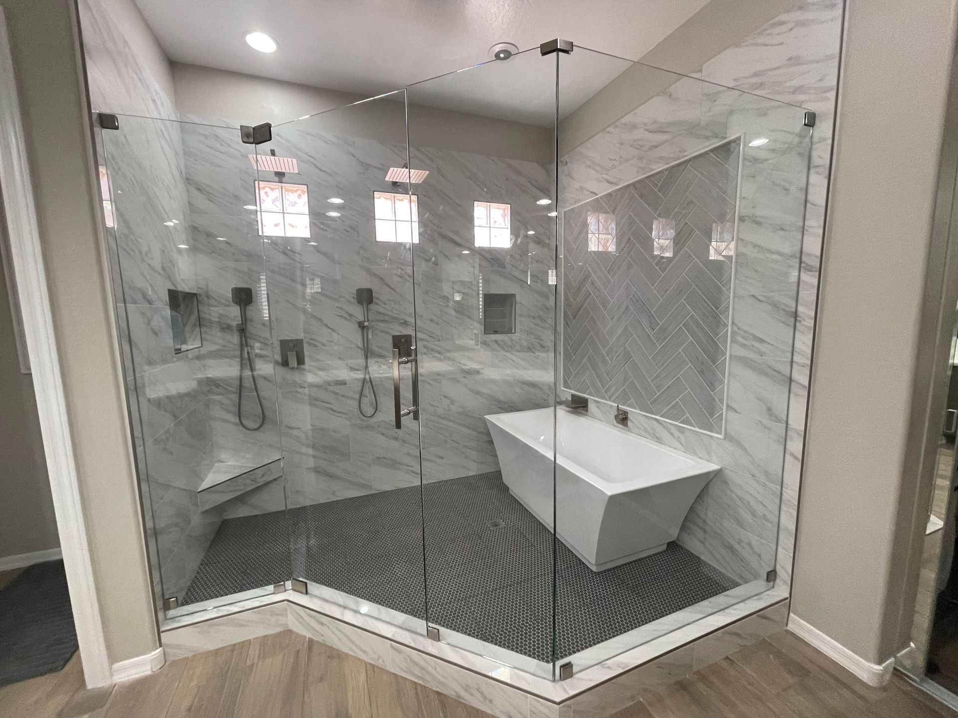Luxurious modern bathroom with glass shower, freestanding tub, marble and wood accents.