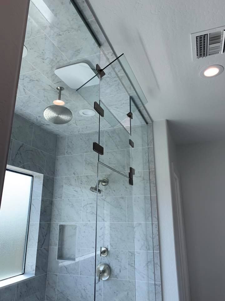 Shower enclosure with sliding glass doors, gray tile walls, and chrome fixtures.