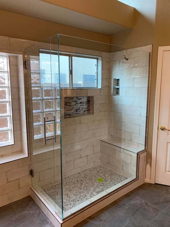 Modern bathroom with glass shower enclosure, tiled walls, and window.