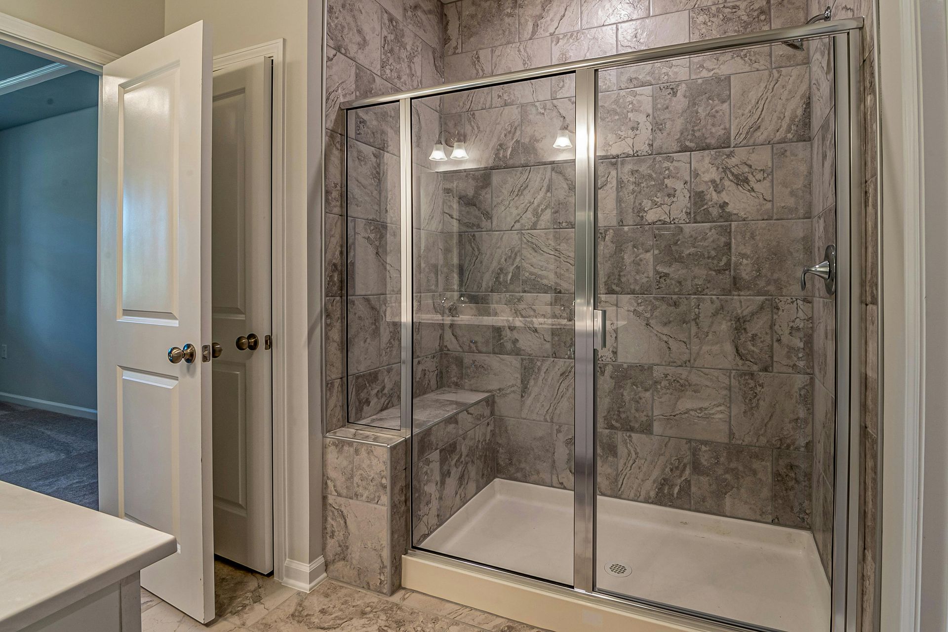 Bathroom with glass shower, tile walls, and a closed door.