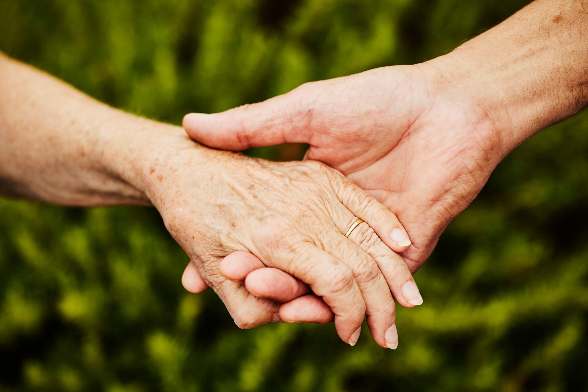 Person's hand on a silver urn surrounded by white flowers and candles, at a memorial service.