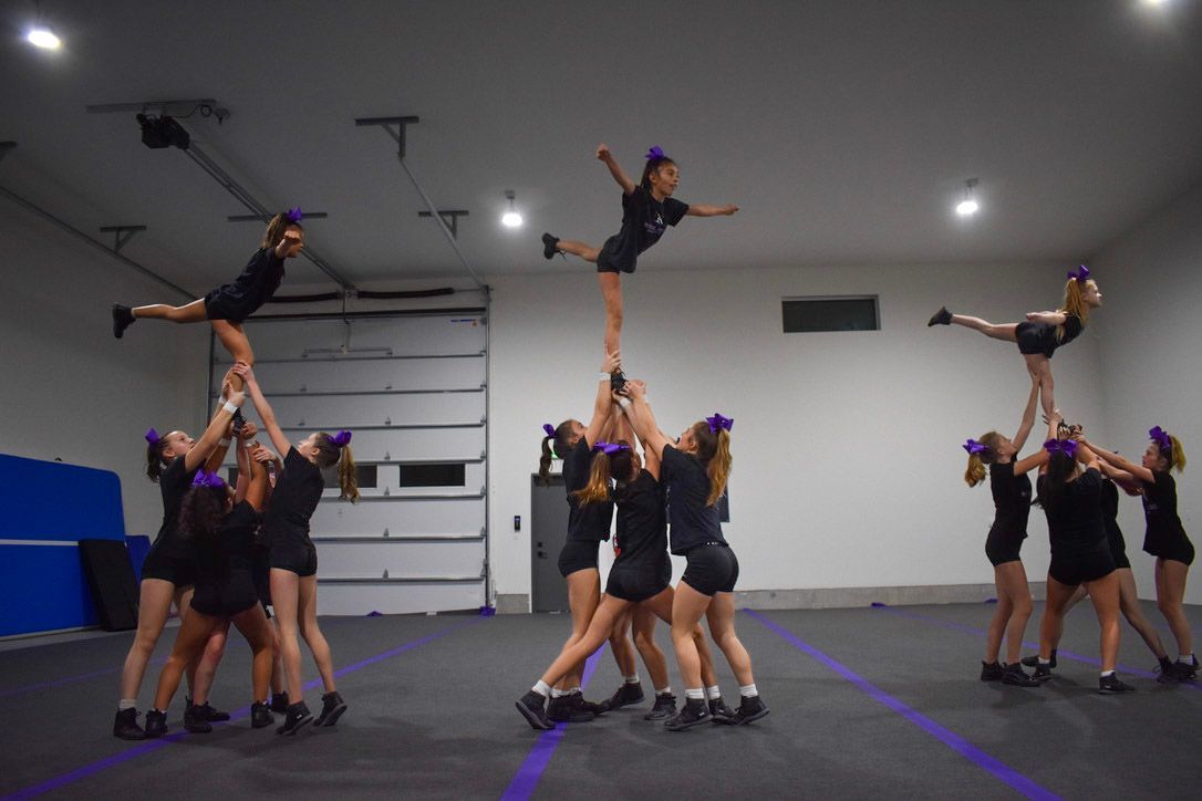 Girl in red shirt doing a handstand, smiling, pigtails.