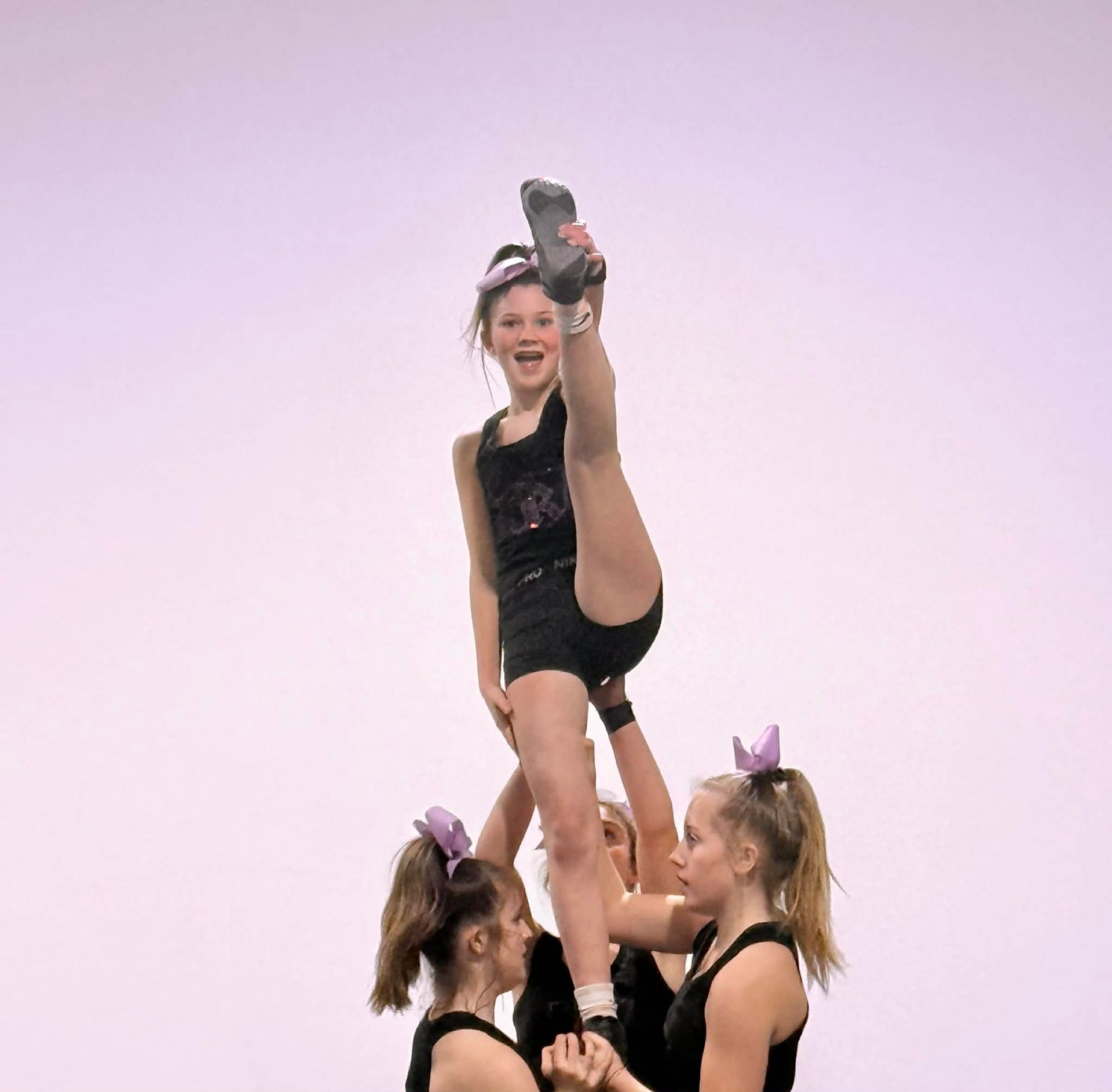 Cheerleaders balanced on shoulders, outdoors on green field.