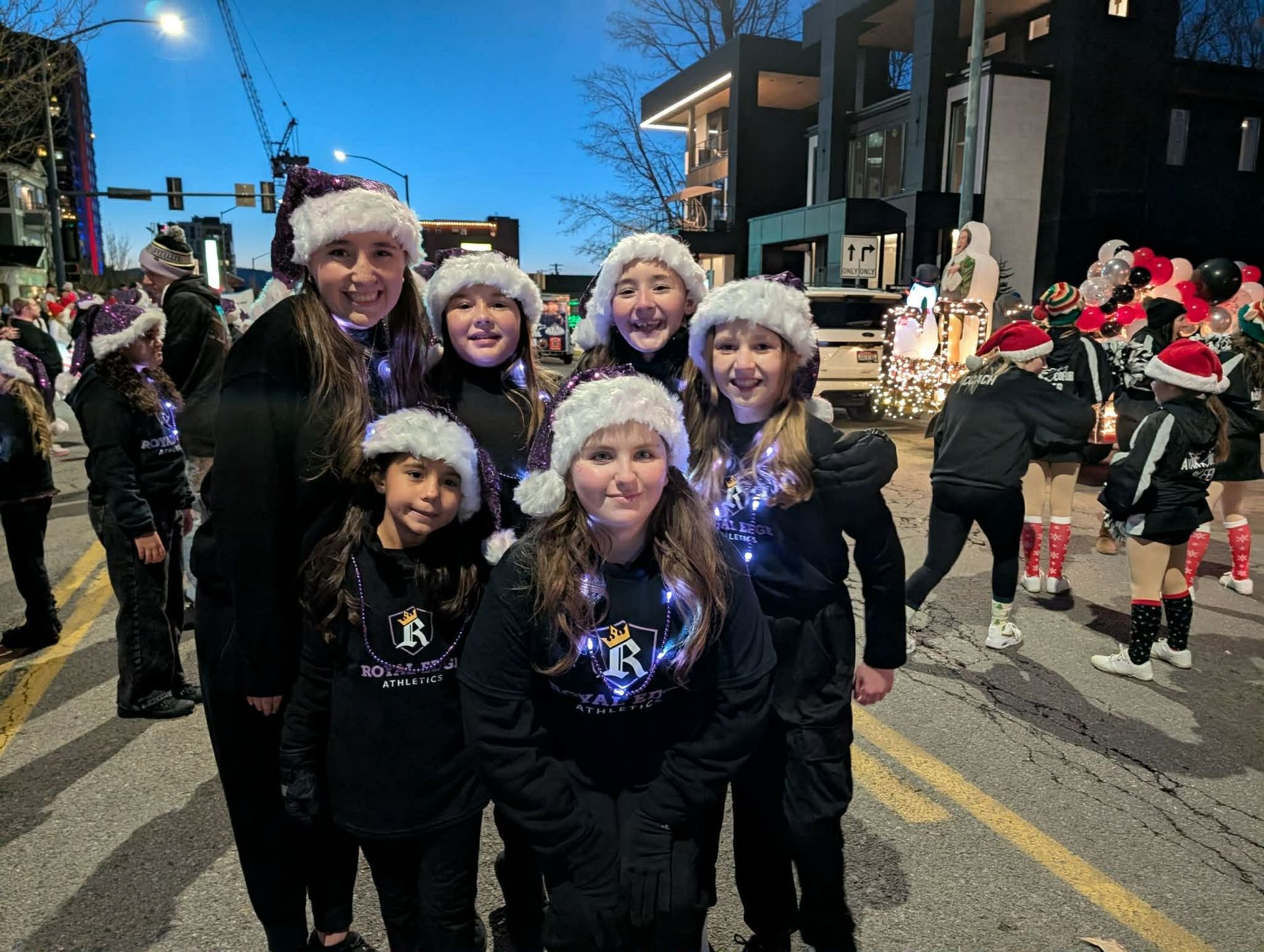 Young girl in purple cheerleading uniform with pom-poms, smiling in a gym.